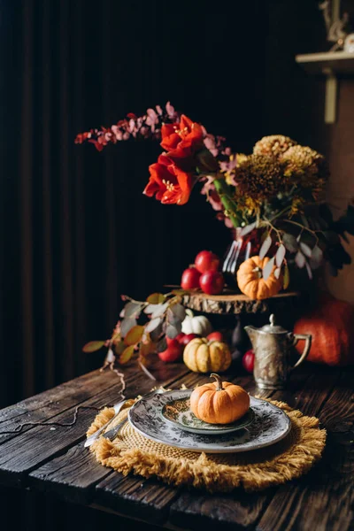 Autumn festive dinner in a rustic style, decorated with flowers and vegetables on a dark background