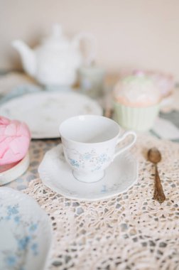 Çay fincanı ve çay tabağı bir masada çay saatiyle birlikte.