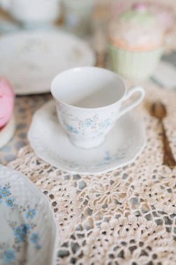 Çay fincanı ve çay tabağı bir masada çay saatiyle birlikte.