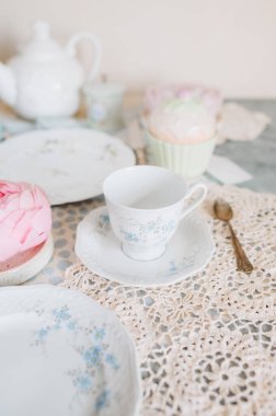 Çay fincanı ve çay tabağı bir masada çay saatiyle birlikte.