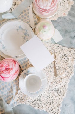 Fotokopi kartı, çay fincanı ve çay fincanı tabağı ve çay saati olan bir masada.