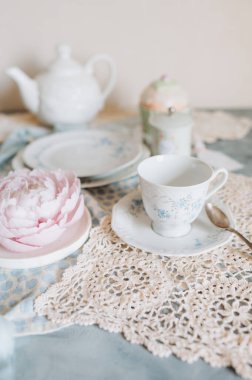 Çay fincanı ve çay tabağı bir masada çay saatiyle birlikte.