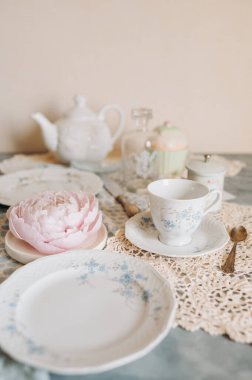 Çay fincanı ve çay tabağı bir masada çay saatiyle birlikte.