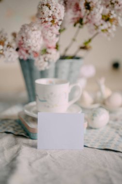 Zarif Paskalya Masası üzerinde Pembe Leylak Çiçekleri ve Festivalsel Dekorasyonlarla mokcup kartı