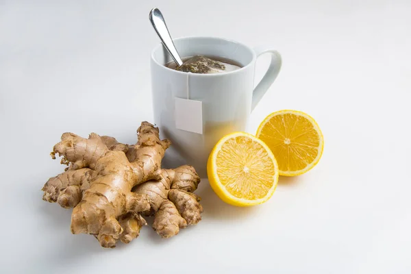 Cup of tea with tea bag with raw ginger and lemon and blank label isolated on white background