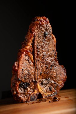 Yüksek Kaliteli Sulu Sanatsal T-Kemik Bifteği Tahta kesim tahtasının üzerinde duruyor
