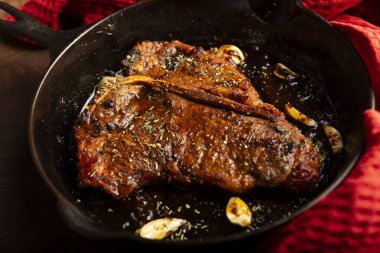 Evdeki dökme demir tavada pişirilmiş sulu bir 16ons T-bone bifteği yakın çekim 