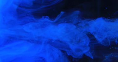 Blue paint drops mixing in water slow motion. Stock footage. Smooth ink swirling and splashing from above underwater leaving ink cloud on black background. High quality 4k footage