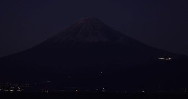 Kışın mavi gökyüzünün arkasında Fuji Dağı 'nın olduğu bir gece. Yüksek kalite 4K görüntü. Numazu bölgesi Heda Shizuoka Japonya 01.25.2023