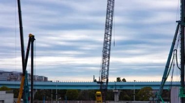 Tren yolu bulutu yakınlarındaki inşaat halindeki vinç zaman çizelgesi. Yüksek kalite 4K görüntü. Koto bölgesi Ariake Tokyo 02.14.2023 Yapım aşamasındaki vinçleri hareket ettiriyor.