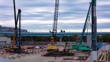 Tren yolu bulutu yakınlarındaki inşaat halindeki vinç zaman çizelgesi. Yüksek kalite 4K görüntü. Koto bölgesi Ariake Tokyo 02.14.2023 Yapım aşamasındaki vinçleri hareket ettiriyor.