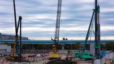 Tren yolu bulutu yakınlarındaki inşaat halindeki vinç zaman çizelgesi. Yüksek kalite 4K görüntü. Koto bölgesi Ariake Tokyo 02.14.2023 Yapım aşamasındaki vinçleri hareket ettiriyor.