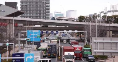 Tokyo bulutlu bir günde şehir caddesinde bir trafik sıkışıklığı. Yüksek kalite 4K görüntü. Koto Bölgesi Ariake Tokyo 02.14.2023 Konteynır limanı nedeniyle sokakta birçok kamyon var.