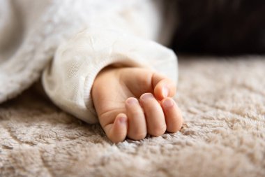 Halıda uyuyan Asyalı bir bebeğin sol eli. Yüksek kalite fotoğraf. 02.25.2023. Bu bir yıllık bir çocuk eli..