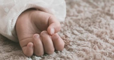 2 x yavaş çekimde uyuyan Asyalı bebek sol elini halıya koydu. Yüksek kalite 4K görüntü. 02.25.2023. Bu bir yaşındaki bir çocuğun eli..