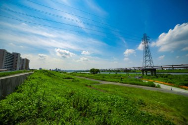 Nehir kenarındaki şehir sokağında trafik sıkışıklığı. Yüksek kalite fotoğraf. Adachi Bölgesi Kouhoku Tokyo Japonya 06.29.2023 Burası Tokyo Arakawa Nehri yakınları.
