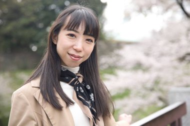 Tokyo 'da kiraz çiçeğinin arkasında Japon bir kadının portresi. Yüksek kalite fotoğraf. Chiyoda bölgesi Tokyo 03.30.2023