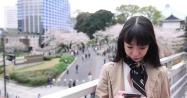 Kiraz çiçeğinin arkasındaki Japon kadının selfie portresi. Yüksek kalite 4K görüntü. Chiyoda bölgesi Tokyo 03.30.2023