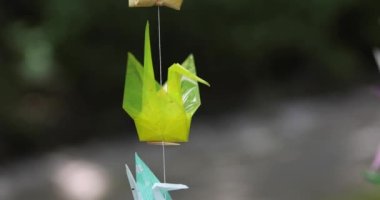 Geleneksel güneşli bir günde rüzgarda sallanan bir kağıt vinç. Yüksek kalite 4K görüntü. Chofu bölgesi Tokyo 07.07.2023 Bu kağıt vincin adı ORIZURU.