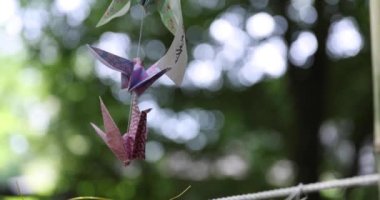 Geleneksel güneşli bir günde rüzgarda sallanan bir kağıt vinç. Yüksek kalite 4K görüntü. Chofu bölgesi Tokyo 07.07.2023 Bu kağıt vincin adı ORIZURU.