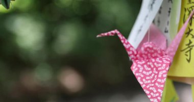 Geleneksel güneşli bir günde rüzgarda sallanan bir kağıt vinç. Yüksek kalite 4K görüntü. Chofu bölgesi Tokyo 07.07.2023 Bu kağıt vincin adı ORIZURU.
