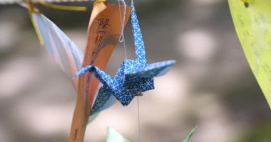 Geleneksel güneşli bir günde rüzgarda sallanan bir kağıt vinç. Yüksek kalite 4K görüntü. Chofu bölgesi Tokyo 07.07.2023 Bu kağıt vincin adı ORIZURU.