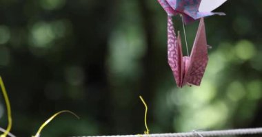 Geleneksel güneşli bir günde rüzgarda sallanan bir kağıt vinç. Yüksek kalite 4K görüntü. Chofu bölgesi Tokyo 07.07.2023 Bu kağıt vincin adı ORIZURU.