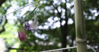 Geleneksel güneşli bir günde rüzgarda sallanan bir kağıt vinç. Yüksek kalite 4K görüntü. Chofu bölgesi Tokyo 07.07.2023 Bu kağıt vincin adı ORIZURU.
