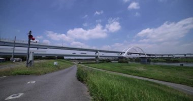 Nehir kenarındaki şehir sokağında trafik sıkışıklığı. Yüksek kalite 4K görüntü. Adachi Bölgesi Kouhoku Tokyo Japonya 06.29.2023 Burası Tokyo Arakawa Nehri yakınları.