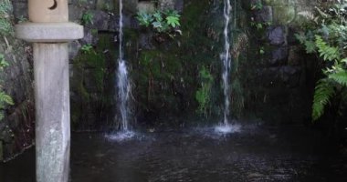 Yazın geleneksel caddede dini bir heykel ve şelale. Yüksek kalite 4K görüntü. Chofu bölgesi Tokyo 07.07.2023 Tokyo 'da geleneksel bir caddedir..