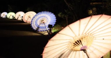 Kış gecelerinde Tachikawa Parkı 'nda elde taşınan aydınlatılmış bir şemsiye. Yüksek kalite 4K görüntü. Tachikawa bölgesi Tokyo 11.13.2023 bir Japon şemsiyesidir..
