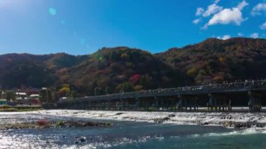 Bulutlar ve Kyoto 'daki Togetsukyo köprüsü yakınlarında turistler. Yüksek kalite 4K görüntü. Kyoto bölgesi Ukyo Kyoto Japonya 12.02.2023 Burası Kyoto 'nun geleneksel bir kasabasıdır..