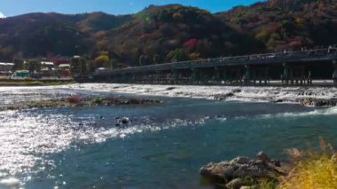 Bulutlar ve Kyoto 'daki Togetsukyo köprüsü yakınlarında turistler. Yüksek kalite 4K görüntü. Kyoto bölgesi Ukyo Kyoto Japonya 12.02.2023 Burası Kyoto 'nun geleneksel bir kasabasıdır..