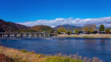 Bulutlar ve Kyoto 'daki Togetsukyo köprüsü yakınlarında turistler. Yüksek kalite 4K görüntü. Kyoto bölgesi Ukyo Kyoto Japonya 12.02.2023 Burası Kyoto 'nun geleneksel bir kasabasıdır..