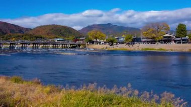 Bulutlar ve Kyoto 'daki Togetsukyo köprüsü yakınlarında turistler. Yüksek kalite 4K görüntü. Kyoto bölgesi Ukyo Kyoto Japonya 12.02.2023 Burası Kyoto 'nun geleneksel bir kasabasıdır..