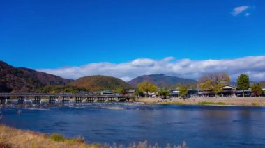 Bulutlar ve Kyoto 'daki Togetsukyo köprüsü yakınlarında turistler. Yüksek kalite 4K görüntü. Kyoto bölgesi Ukyo Kyoto Japonya 12.02.2023 Burası Kyoto 'nun geleneksel bir kasabasıdır..