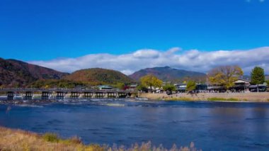 Bulutlar ve Kyoto 'daki Togetsukyo köprüsü yakınlarında turistler. Yüksek kalite 4K görüntü. Kyoto bölgesi Ukyo Kyoto Japonya 12.02.2023 Burası Kyoto 'nun geleneksel bir kasabasıdır..