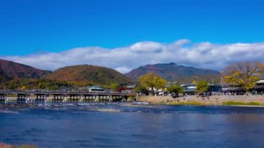 Bulutlar ve Kyoto 'daki Togetsukyo köprüsü yakınlarında turistler. Yüksek kalite 4K görüntü. Kyoto bölgesi Ukyo Kyoto Japonya 12.02.2023 Burası Kyoto 'nun geleneksel bir kasabasıdır..