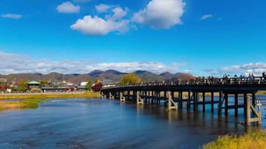 Bulutlar ve Kyoto 'daki Togetsukyo köprüsü yakınlarında turistler. Yüksek kalite 4K görüntü. Kyoto bölgesi Ukyo Kyoto Japonya 12.02.2023 Burası Kyoto 'nun geleneksel bir kasabasıdır..