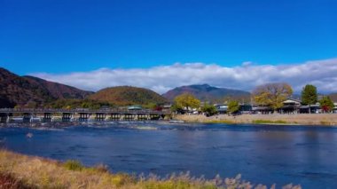 Bulutlar ve Kyoto 'daki Togetsukyo köprüsü yakınlarında turistler. Yüksek kalite 4K görüntü. Kyoto bölgesi Ukyo Kyoto Japonya 12.02.2023 Burası Kyoto 'nun geleneksel bir kasabasıdır..