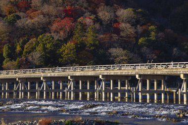 Kyoto 'daki Katsuragawa nehri yakınlarındaki Togetsukyo köprüsünde sonbahar telefoto çekimi. Yüksek kalite fotoğraf. Kyoto bölgesi Ukyo Kyoto Japonya 12.02.2023 Burası Kyoto 'nun geleneksel bir kasabasıdır..