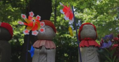 Tokyo gündüz el kamerasında kırmızı şapka takan heykel koruyucusu. Tokyo Minato Bölgesi - 07.25.2019: Geleneksel tapınakta bulunan eski bir heykel.