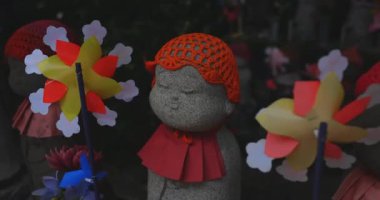 Tokyo gündüz el kamerasında kırmızı şapka takan heykel koruyucusu. Tokyo Minato Bölgesi - 07.25.2019: Geleneksel tapınakta bulunan eski bir heykel.