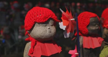 Tokyo gündüz el kamerasında kırmızı şapka takan heykel koruyucusu. Tokyo Minato Bölgesi - 07.25.2019: Geleneksel tapınakta bulunan eski bir heykel.