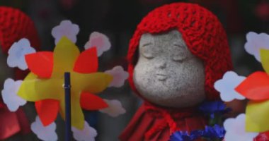 Tokyo gündüz el kamerasında kırmızı şapka takan heykel koruyucusu. Tokyo Minato Bölgesi - 07.25.2019: Geleneksel tapınakta bulunan eski bir heykel.