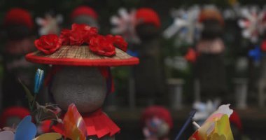 Odaklanırken kırmızı şapka takan heykel koruyucusu. Tokyo Minato Bölgesi - 07.25.2019: Geleneksel tapınakta bulunan eski bir heykel.