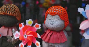 Tokyo gündüz el kamerasında kırmızı şapka takan heykel koruyucusu. Tokyo Minato Bölgesi - 07.25.2019: Geleneksel tapınakta bulunan eski bir heykel.