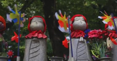 Tokyo gündüz el kamerasında kırmızı şapka takan heykel koruyucusu. Tokyo Minato Bölgesi - 07.25.2019: Geleneksel tapınakta bulunan eski bir heykel.