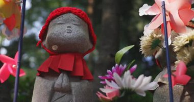 Tokyo gündüz el kamerasında kırmızı şapka takan heykel koruyucusu. Tokyo Minato Bölgesi - 07.25.2019: Geleneksel tapınakta bulunan eski bir heykel.