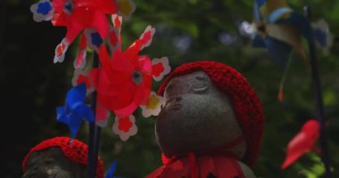 Tokyo gündüz el kamerasında kırmızı şapka takan heykel koruyucusu. Tokyo Minato Bölgesi - 07.25.2019: Geleneksel tapınakta bulunan eski bir heykel.